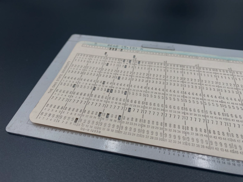 A punched card positioned in the card gauge showing the alignment of markings on the gauge to punches on the card.