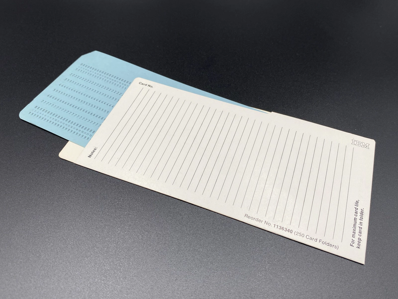 The card folder on a flat surface with a Blue IBM Ziffernkarte No 5 partially inserted.