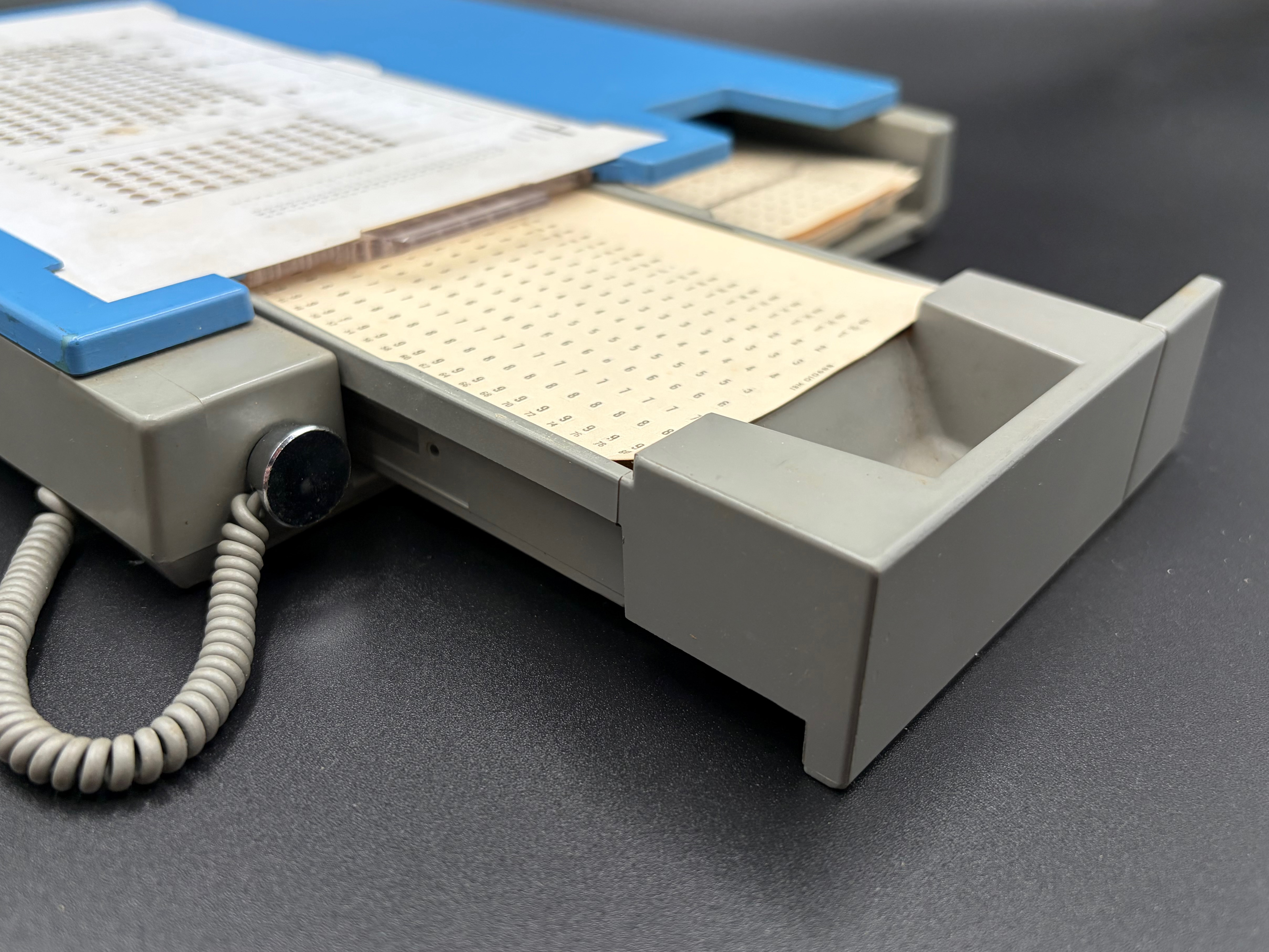 Detail of the open sliding drawer where the perforated card is inserted for punching. An unpunched card is shown inserted.