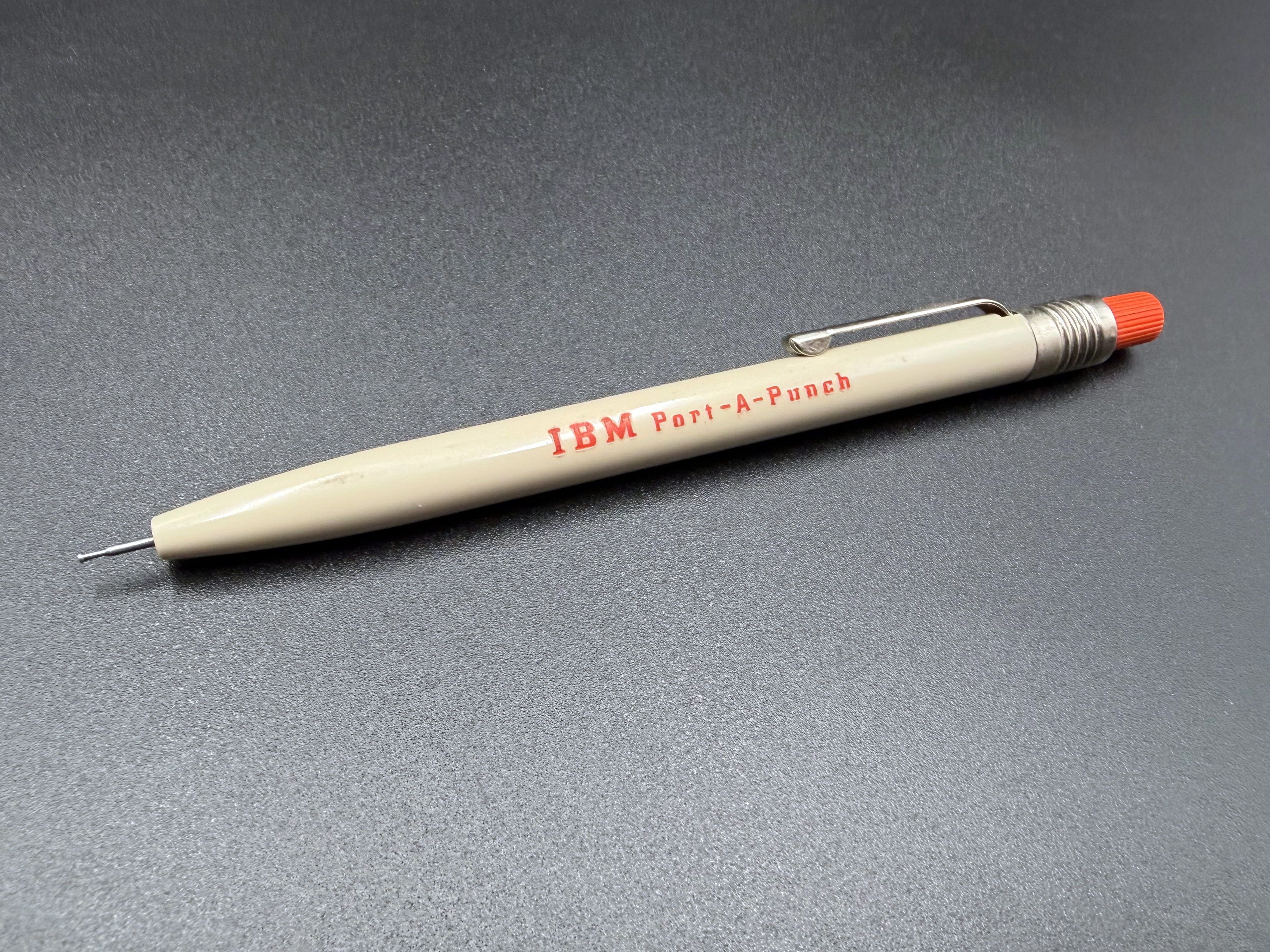 A single IBM Port-a-Punch Stylus removed from the box. The stylus punch tip is extended.