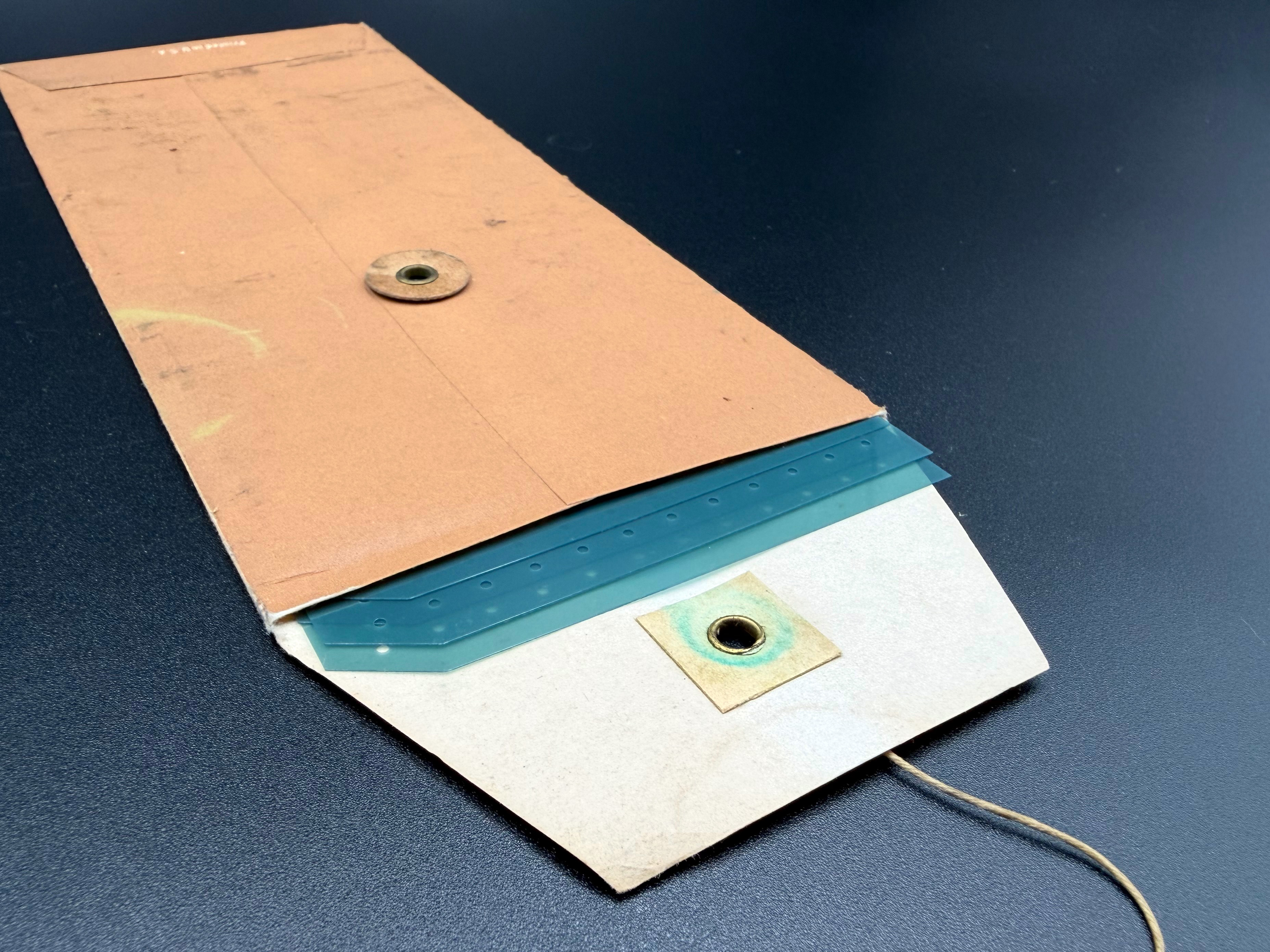 A number of spare punching templates partly removed from the envelope showing the open rear flap.